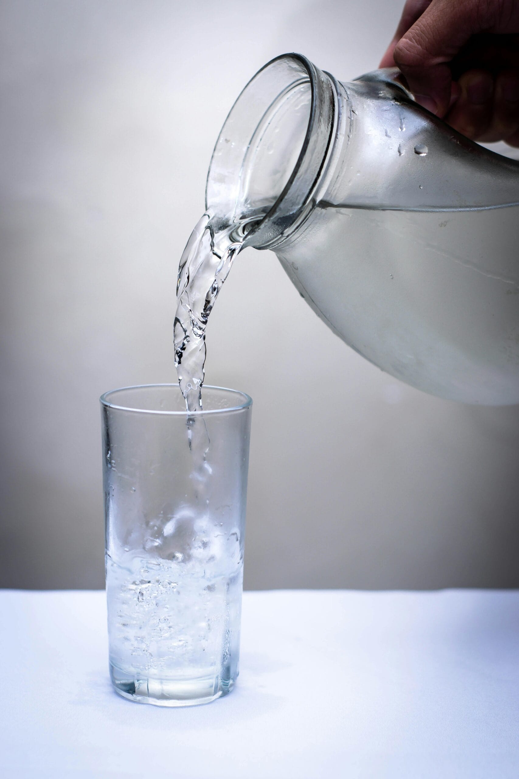 A clear glass of purified water being poured from a glass pitcher. At Longevity Vault, we help identify accelerated aging risks—including toxins in drinking water—that could be holding you back. Learn how to eliminate contaminants and apply high-impact longevity fixes to optimize your health.