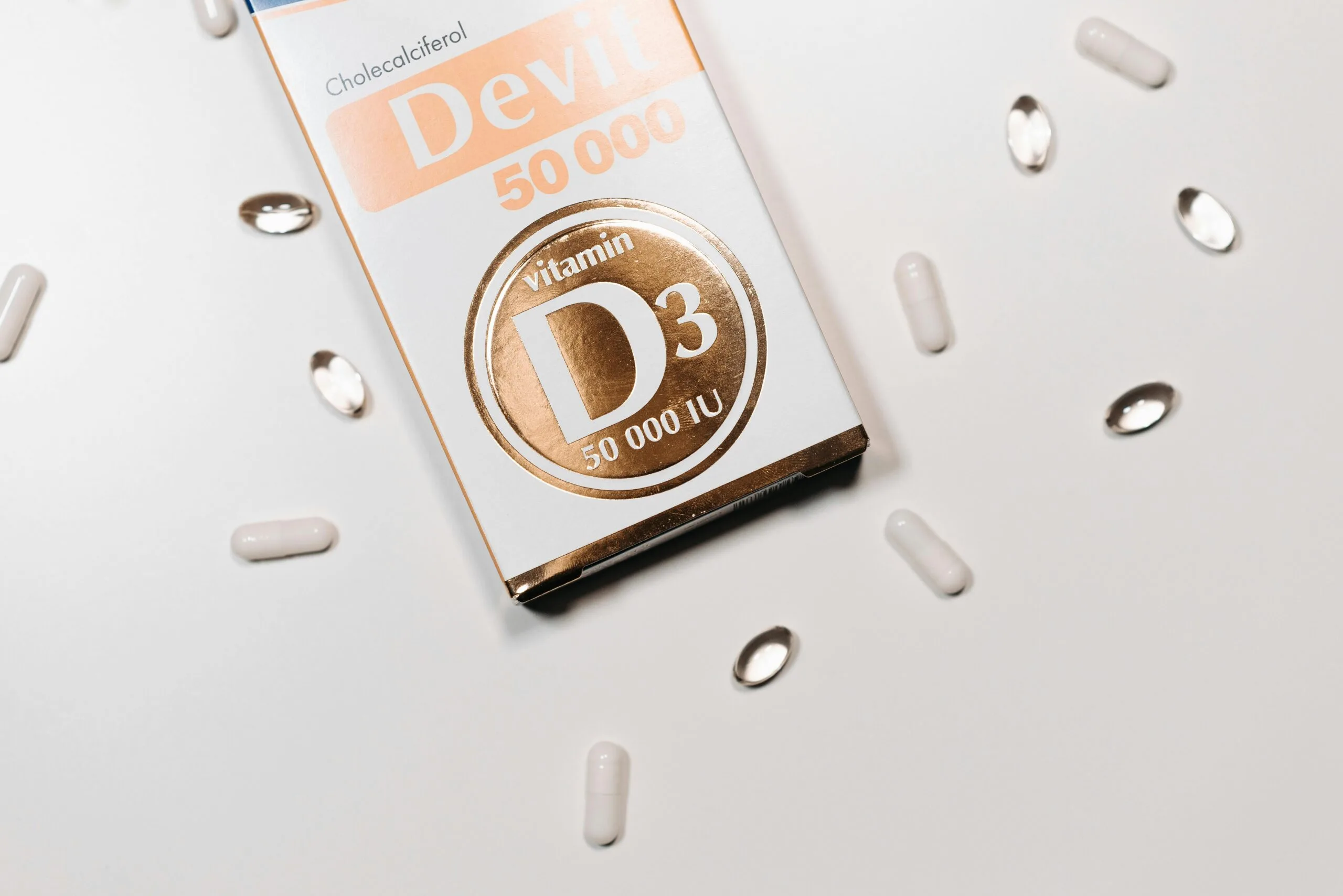 vitamin d3 50000IU supplement packaging scaled High-dose vitamin D3 supplement box labeled 50,000 IU with scattered capsules